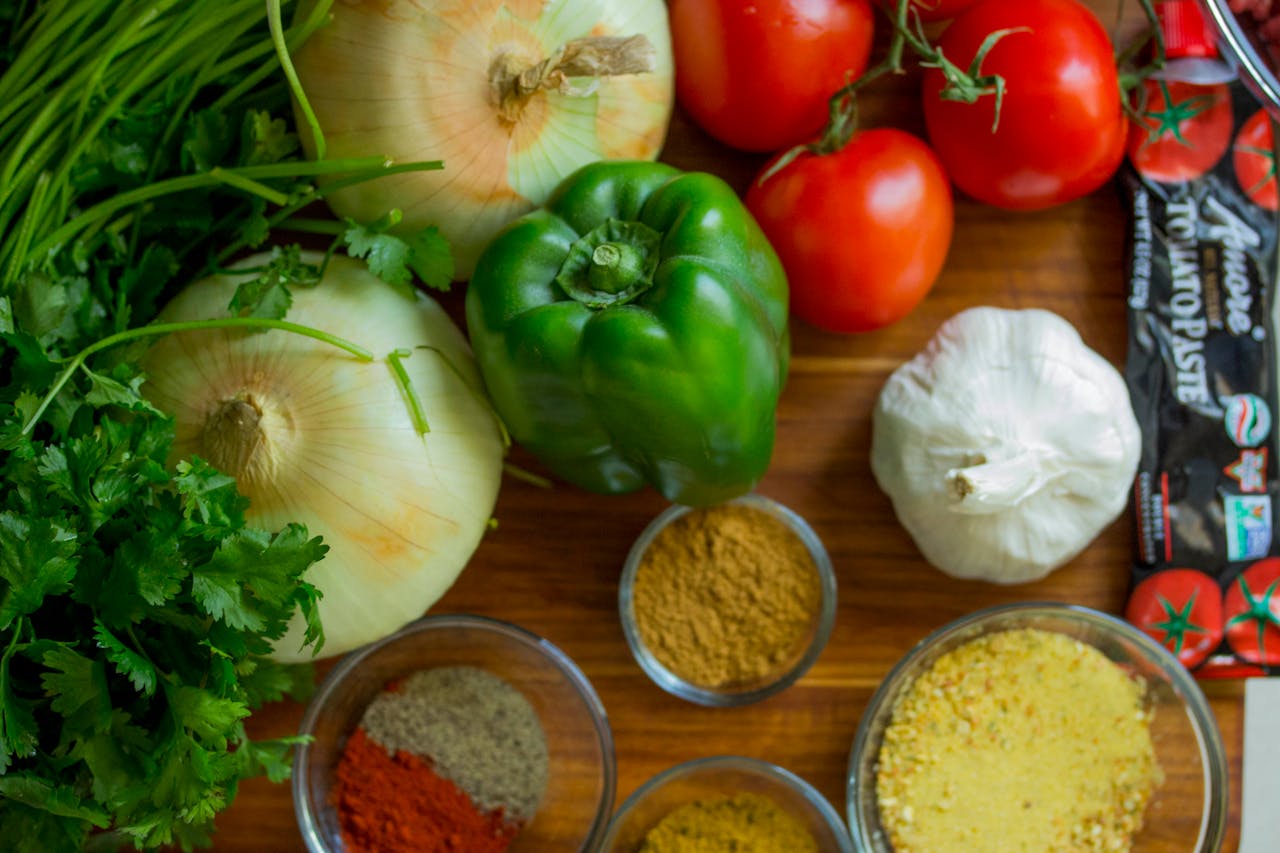 contact-img-01 An assortment of fresh vegetables and spices on a wooden table for healthy cooking.